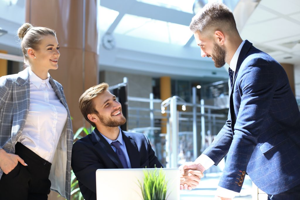 Businessman shaking hands to seal a deal with his partner and colleagues in office.
