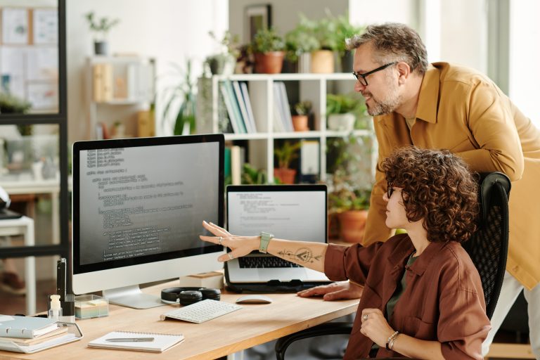 Young confident programmer pointing at data on computer screen