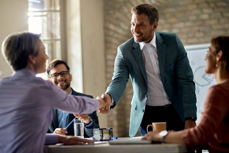 Happy businessman greeting a female colleague on a meeting in the office.